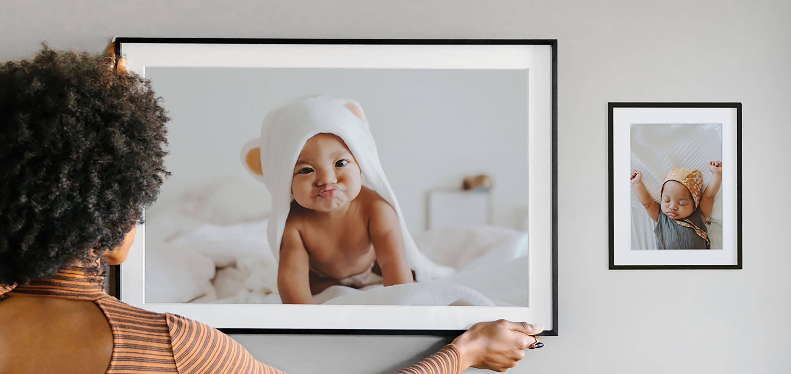 Woman hanging large frame to complete minimalist gallery wall