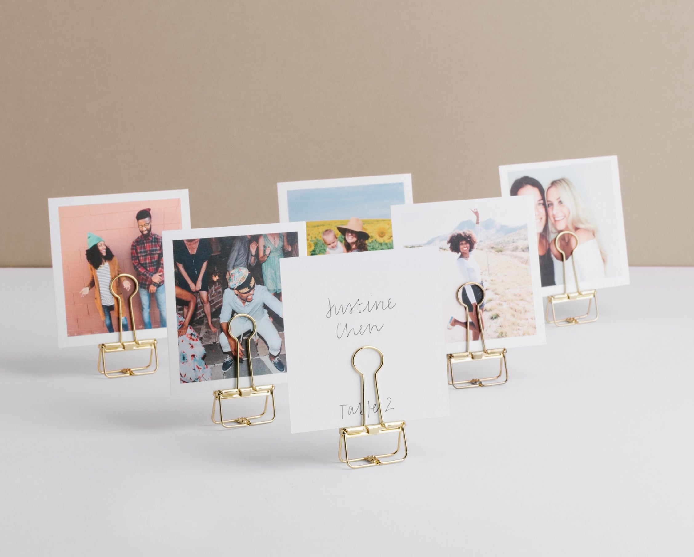 Photos of friends and family featured on Artifact Uprising Square Prints which are displayed on gold binder clips