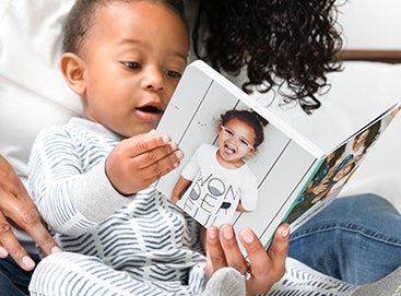 Little boy reading Artifact Uprising Baby Board Book with mother