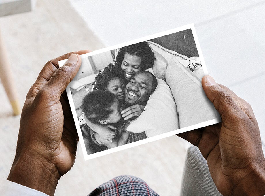 Man holding up DIY postcard with family photo on front