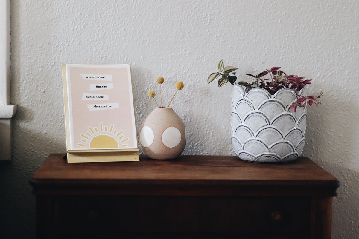 Brass Easel Print Display with inspiring words on dresser next to plants