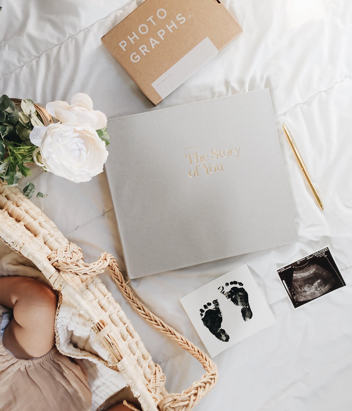 Story of You Baby Book next to baby in bassinet on bed